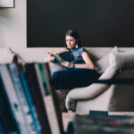 Young,Beautiful,Woman,Enjoys,Reading,Sitting,On,A,Comfortable,Couch.